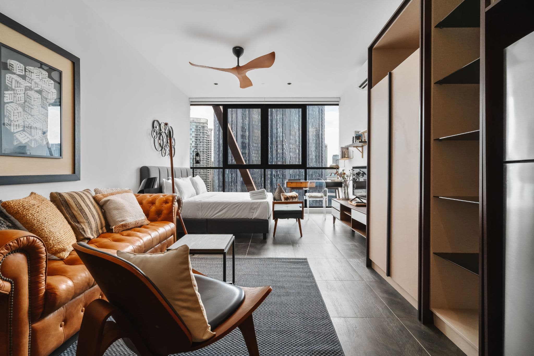 Studio serviced apartment in Kuala Lumpur with a leather sofa, king bed and floor-to-ceiling windows facing city skyscrapers